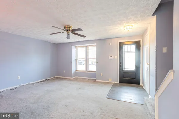 a view of a livingroom with a chandelier fan and windows