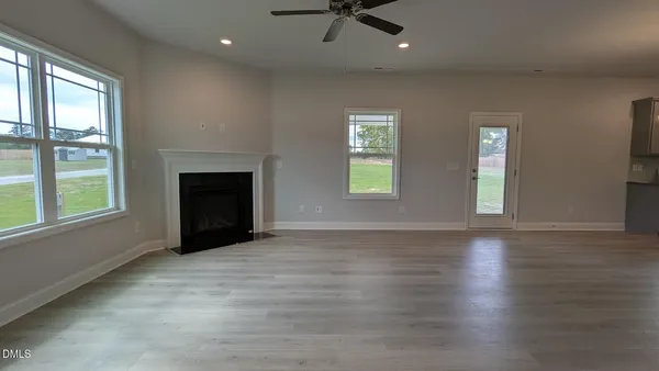 an empty room with windows fireplace and wooden floor