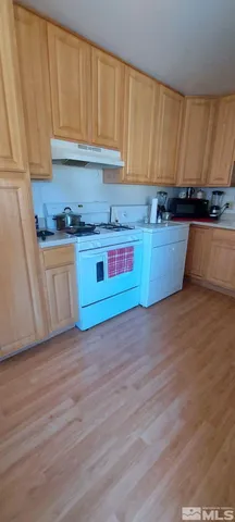 a kitchen with granite countertop wooden cabinets a stove and a sink