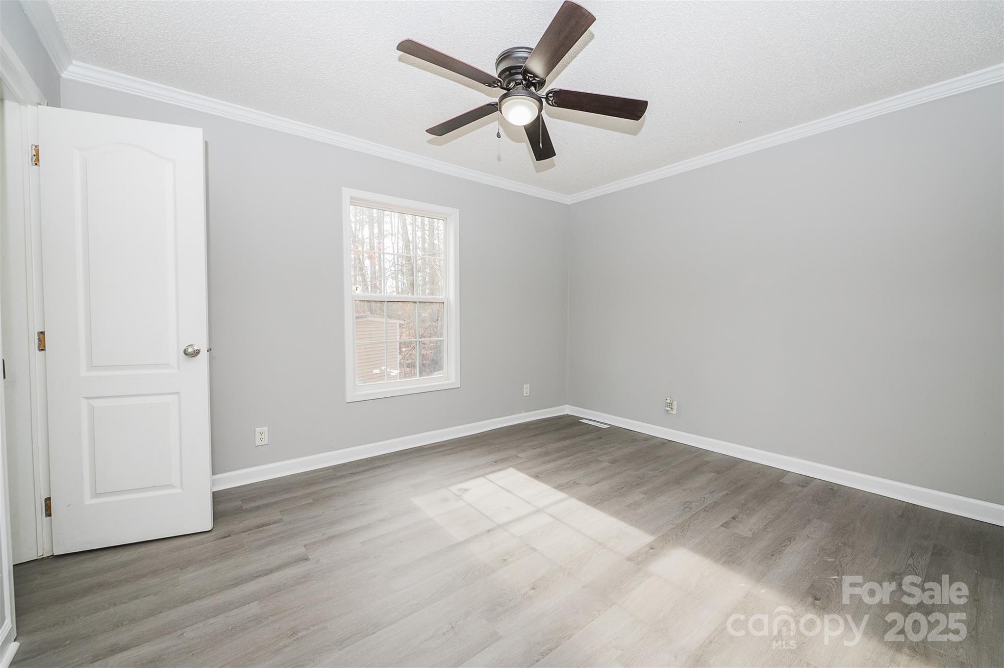 8226 Malibu Road Mount Pleasant, NC 28124 - Photo 16 of 44 an empty room with wooden floor ceiling fan and windows