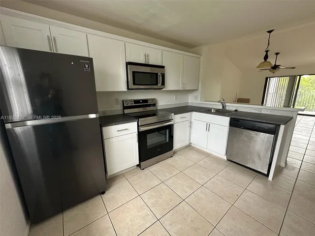 a kitchen with white cabinets and refrigerator
