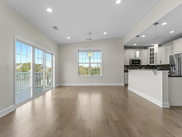 a view of kitchen with kitchen island wooden floor and stainless steel appliances