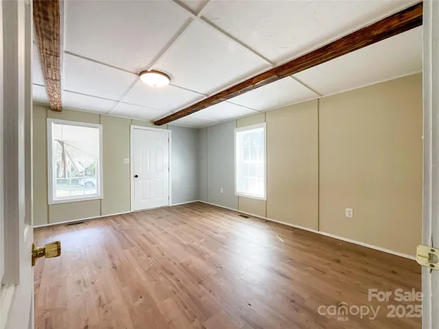 a view of an empty room with wooden floor and a window