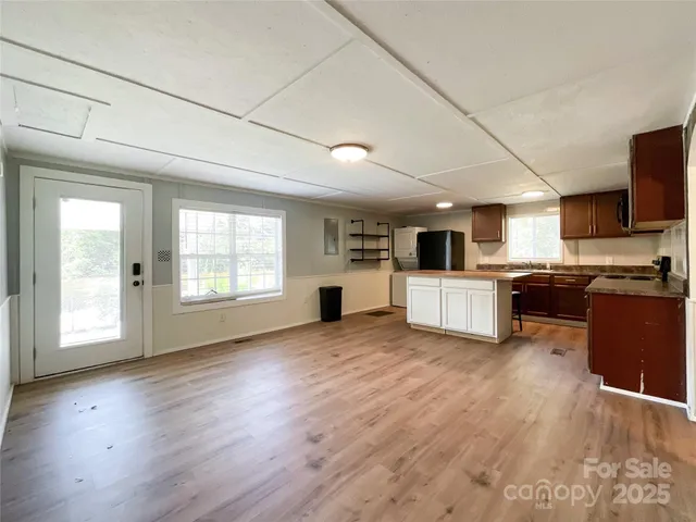 a large white kitchen with stainless steel appliances granite countertop a stove and a wooden floors
