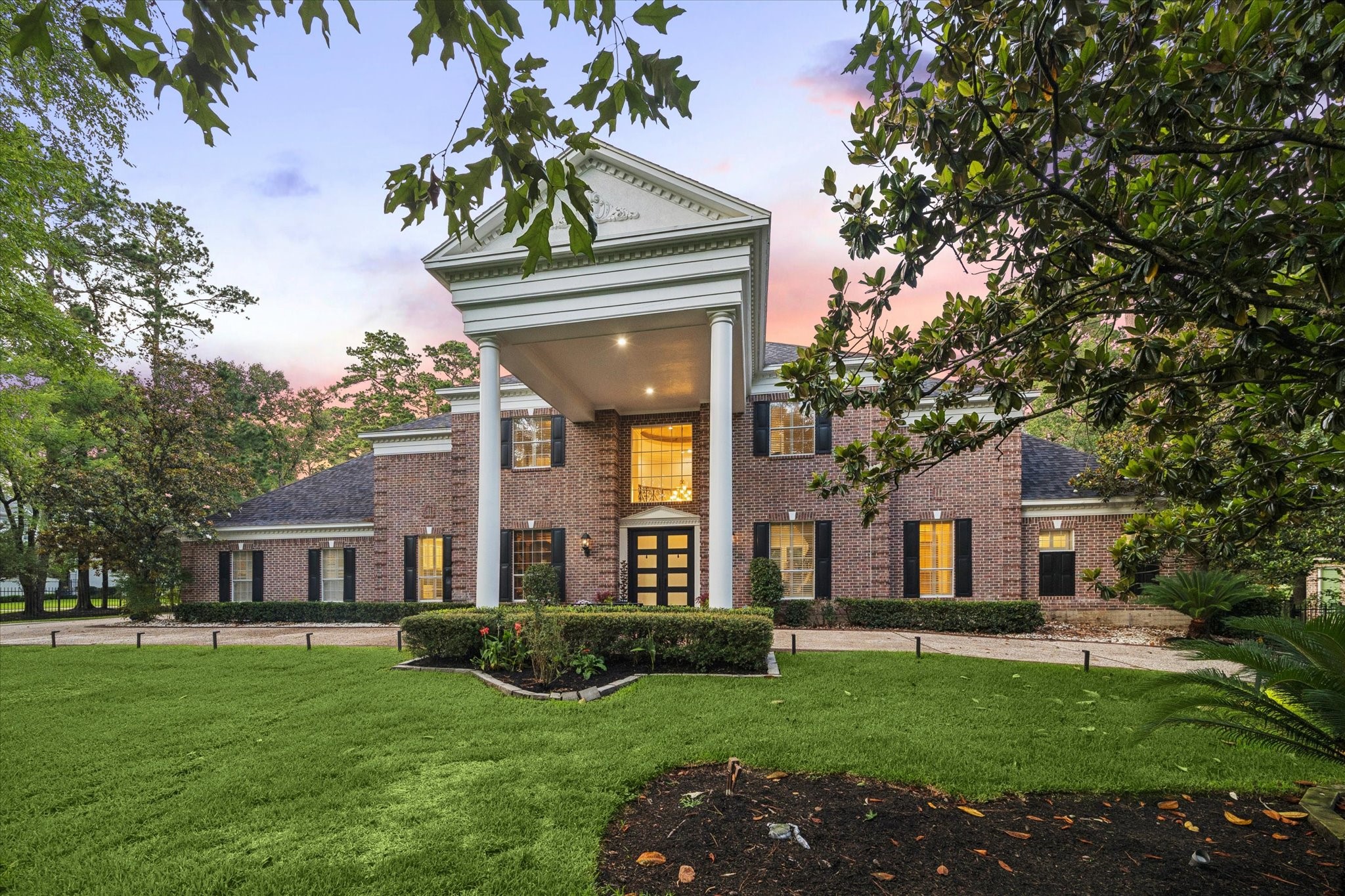 35 North Regent Oak Spring, TX 77381 - Photo 3 of 43 A breathtaking two-story columned portico creates a truly grand arrival experience, reminiscent of a distinguished private estate. Framed by mature trees and lush landscaping, this stately entrance serves as a striking architectural focal point, welcoming residents and guests alike with timeless elegance, sophistication, and grace.