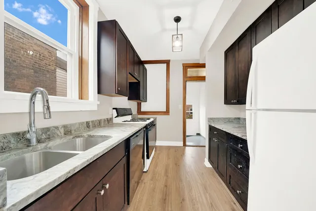 a kitchen with stainless steel appliances granite countertop a sink a stove and a wooden floors