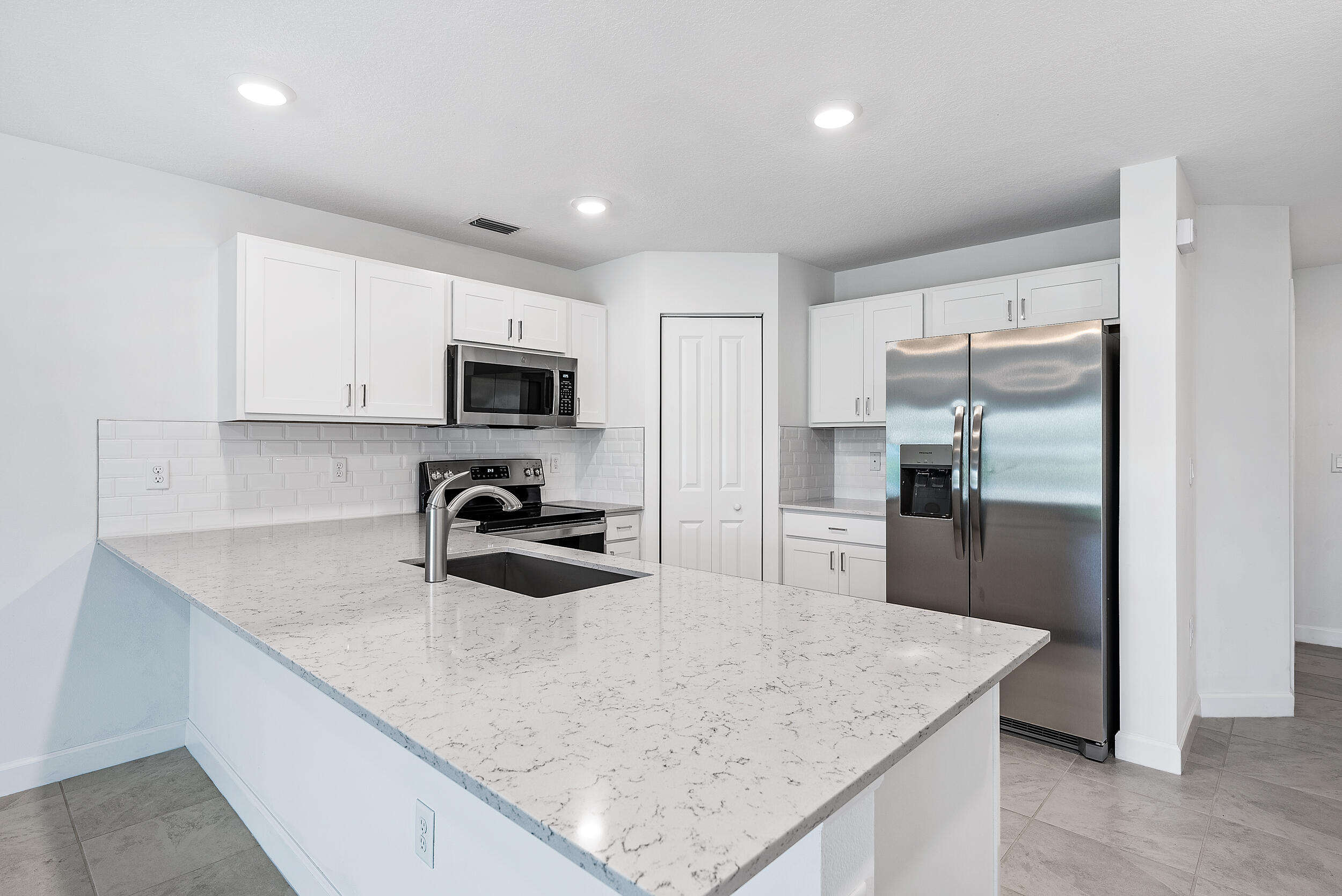 4215 Bent River Road Lake Worth, FL 33467 - Photo 4 of 29 a kitchen with a refrigerator a microwave a sink and cabinets