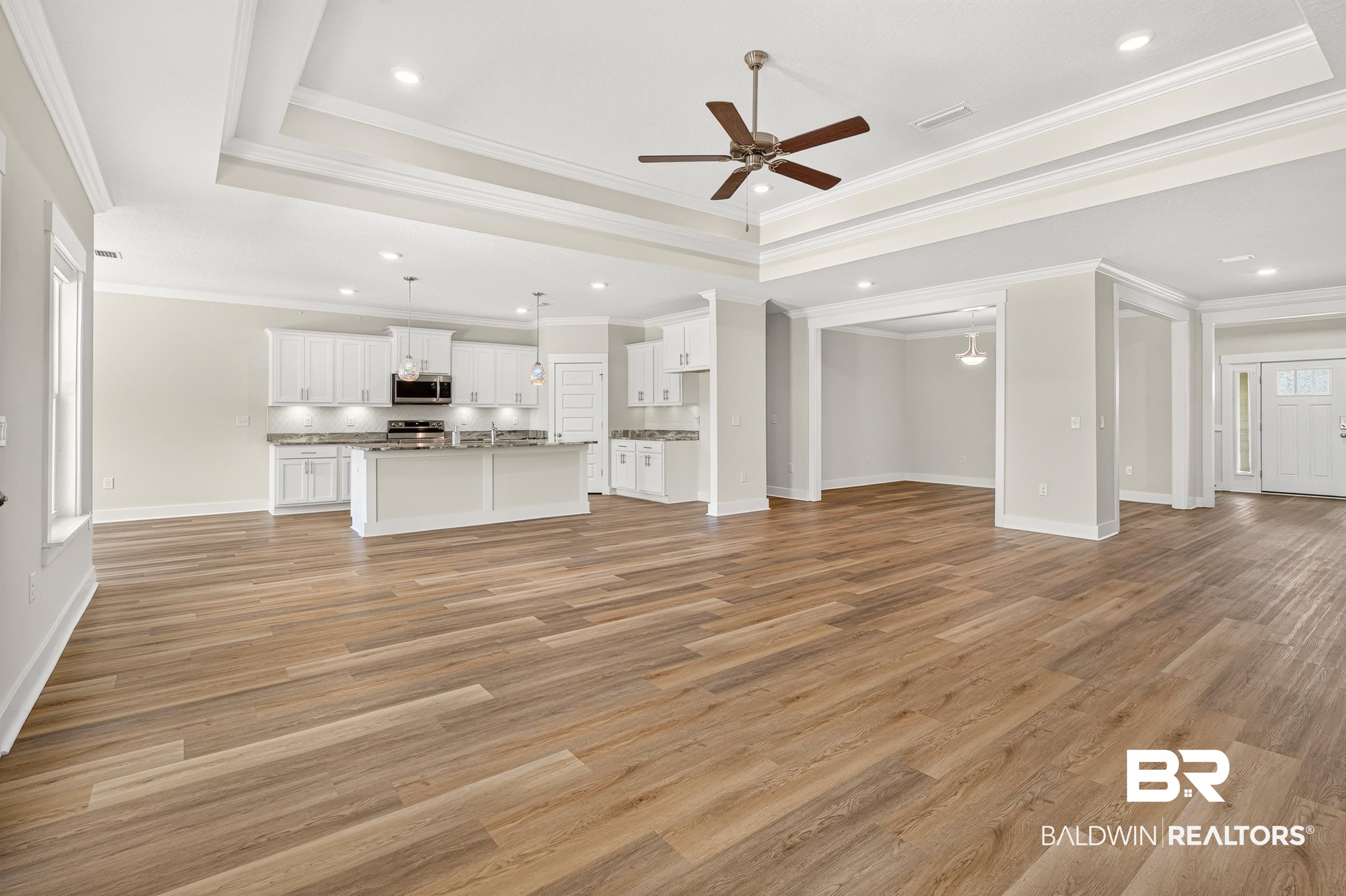 1724 Partridge Street Foley, AL 36535 - Photo 15 of 62 Open-concept living space featuring wood-finish flooring, a tray ceiling with a ceiling fan, recessed lighting, and a white kitchen with an island and pendant lighting