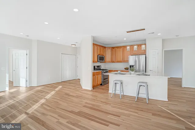 a kitchen with stainless steel appliances granite countertop a stove top oven a sink dishwasher and a refrigerator with wooden floor