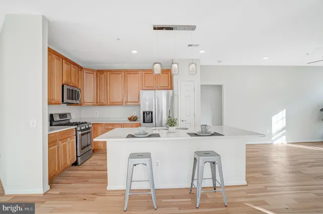 a kitchen with stainless steel appliances kitchen island granite countertop a stove top oven a sink a dining table and chairs with wooden floor