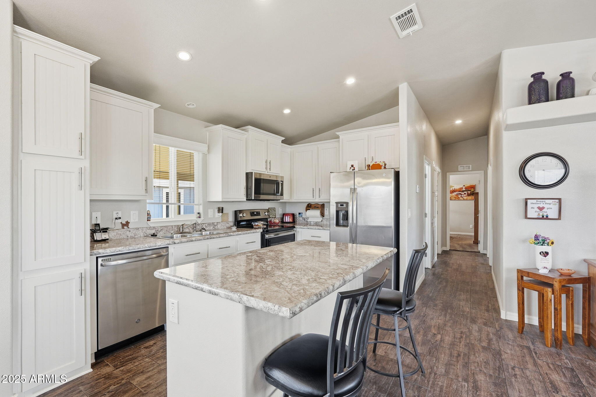 8865 East Baseline Road, Unit 558 Mesa, AZ 85209 - Photo 15 of 54 a kitchen with stainless steel appliances granite countertop a kitchen island hardwood floor sink stove and white cabinets