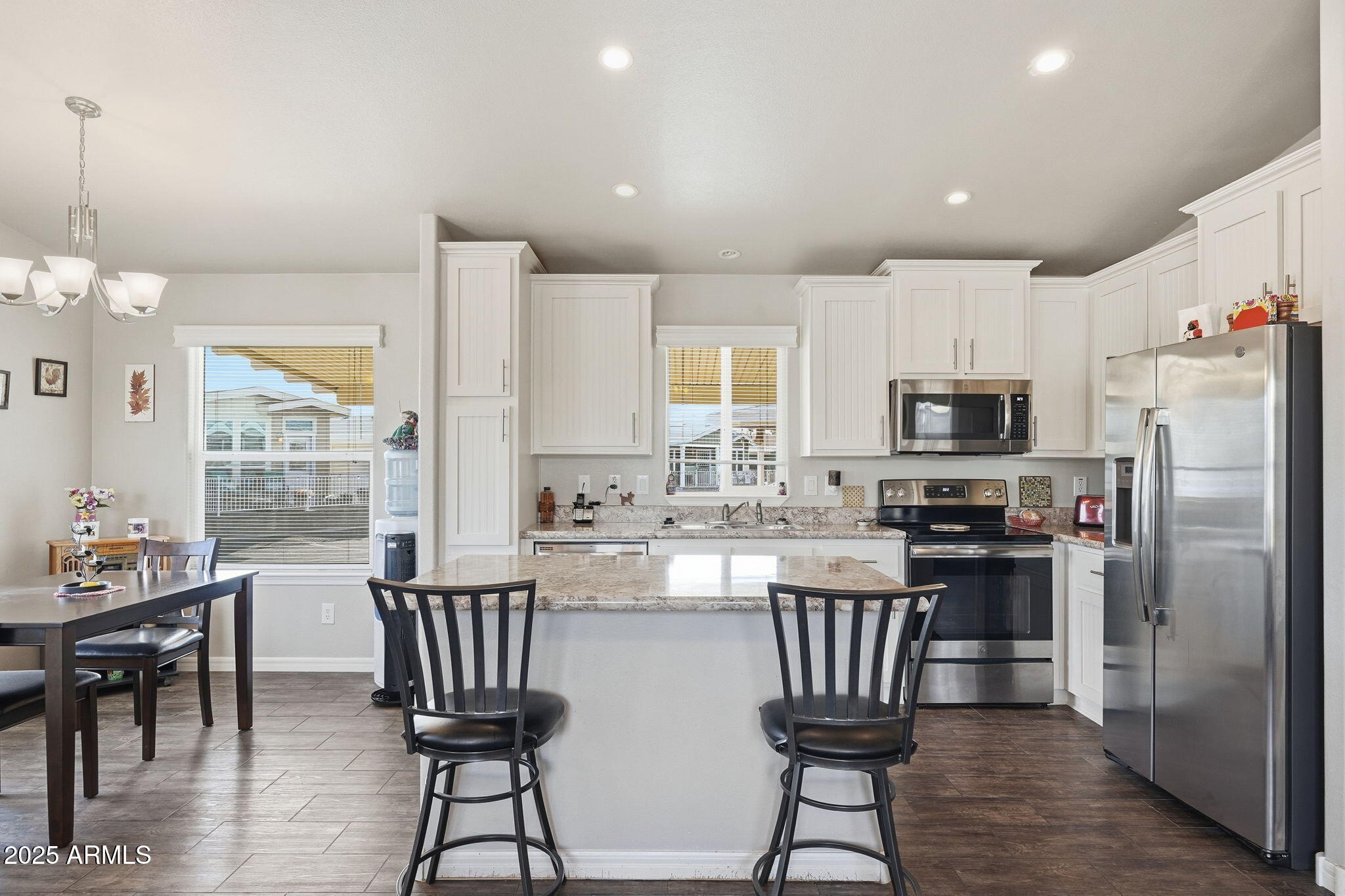 8865 East Baseline Road, Unit 558 Mesa, AZ 85209 - Photo 16 of 54 a kitchen with stainless steel appliances granite countertop a stove top oven a refrigerator a sink dishwasher a dining table and chairs with wooden floor