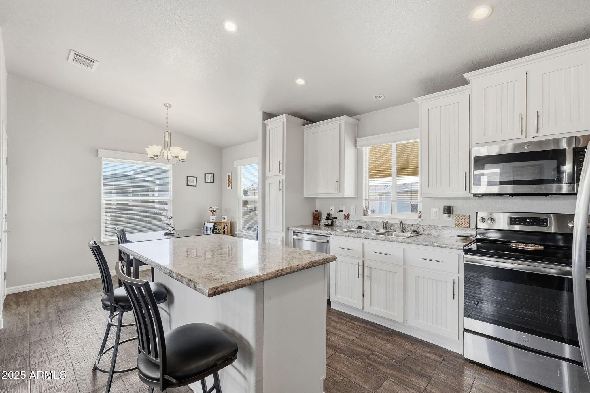 8865 East Baseline Road, Unit 558 Mesa, AZ 85209 - Photo 17 of 54 a kitchen with stainless steel appliances granite countertop a stove a sink a microwave a dining table and chairs