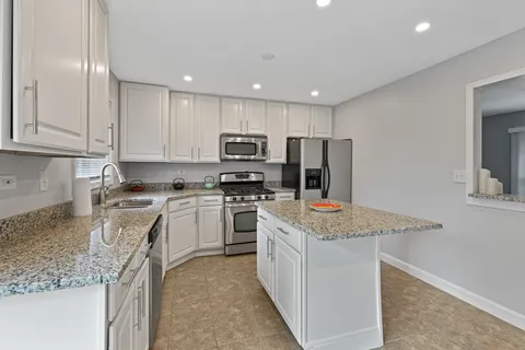 a kitchen with stainless steel appliances granite countertop a sink stove and refrigerator