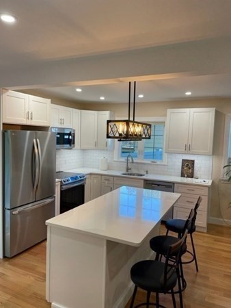 47 Bow Street Saugus, MA 01906 - Photo 21 of 31 a kitchen with a table chairs wooden floor and stainless steel appliances