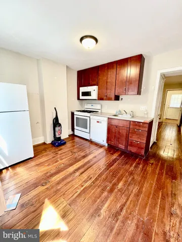 a kitchen with stainless steel appliances wooden floor and a refrigerator