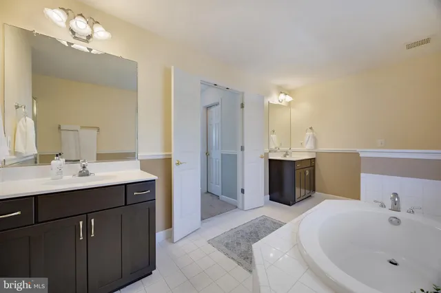 a spacious bathroom with a bathtub sink mirror and shower