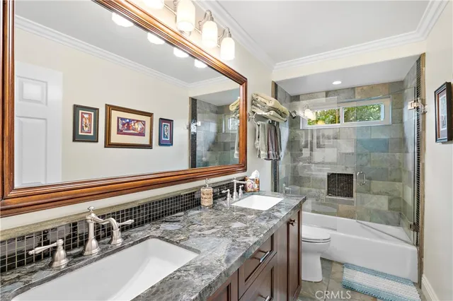 a bathroom with a granite countertop double vanity sink a mirror a bathtub and shower