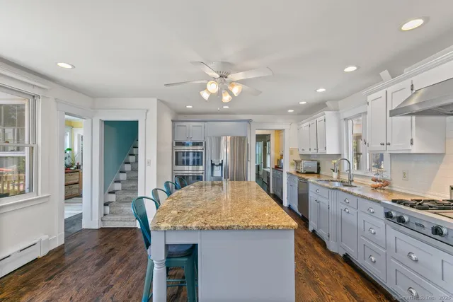 a kitchen with granite countertop kitchen island wooden floor center island and stainless steel appliances
