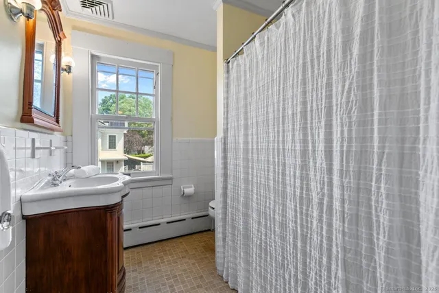 a bathroom with a sink a mirror and next to a window
