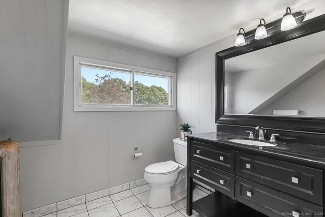 a bathroom with a toilet sink double vanity and mirror