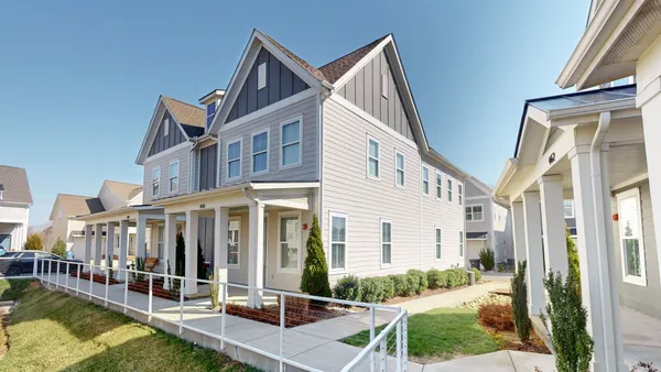 a view of a white house with a small yard and potted plants