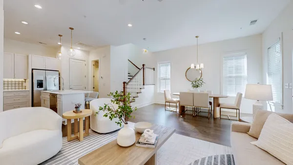 a living room with furniture kitchen view and a chandelier
