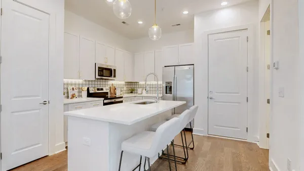 a kitchen with a refrigerator a stove a sink dishwasher and white cabinets with wooden floor