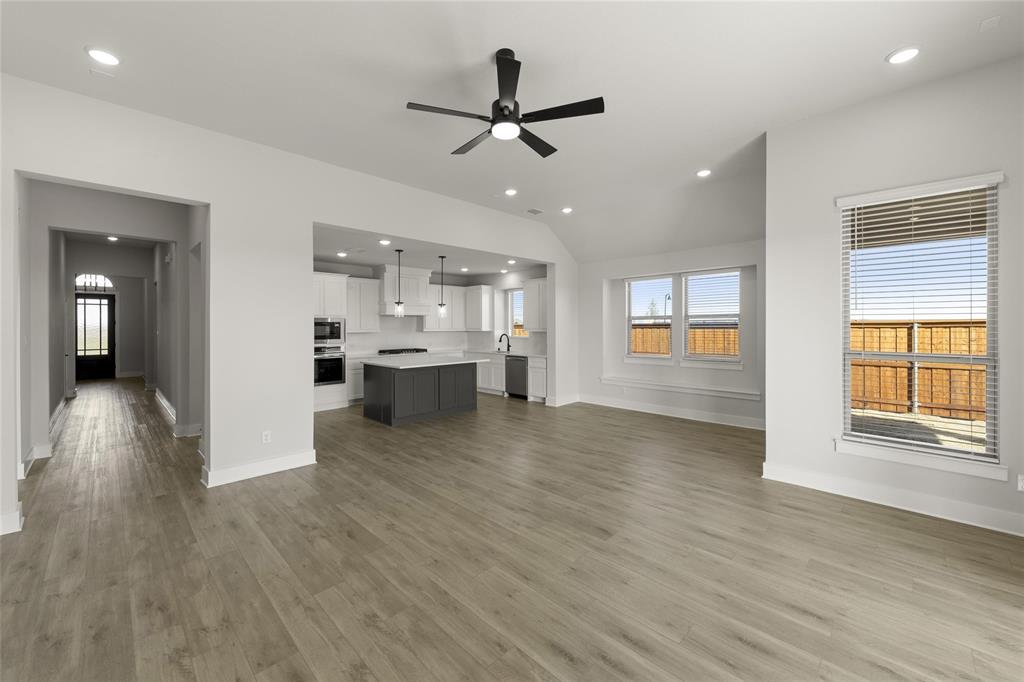 1503 Robinson Road Forney, TX 75126 - Photo 12 of 34 a view of an empty room and kitchen with wooden floor and a ceiling fan