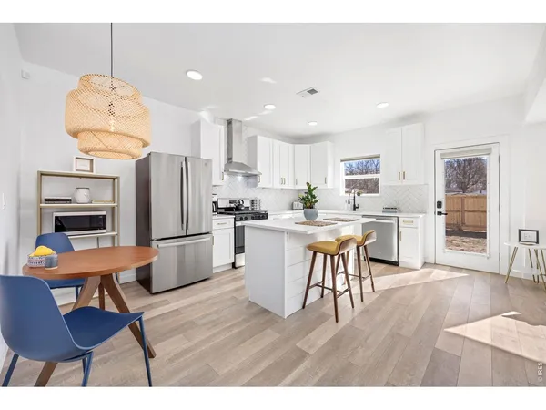 a open kitchen with stainless steel appliances wooden floor and a refrigerator