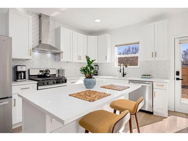 a white kitchen with a stove a white table and chairs