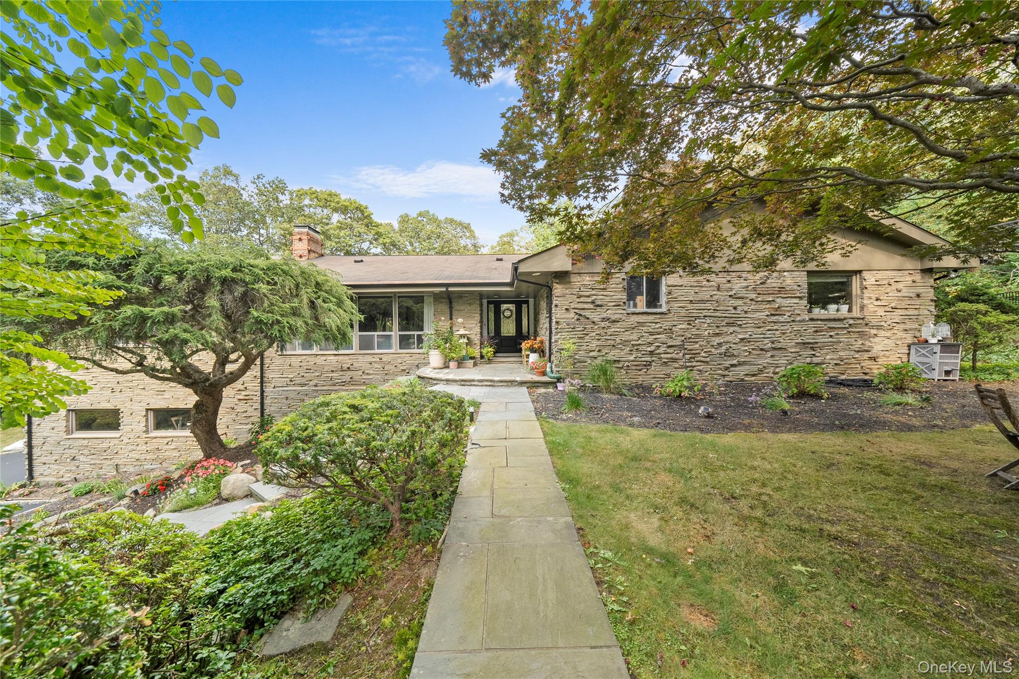 55 Rolling Hill Lane Old Westbury, NY 11568 - Photo 1 of 48 View of front of house with a front lawn, stone siding, and a chimney