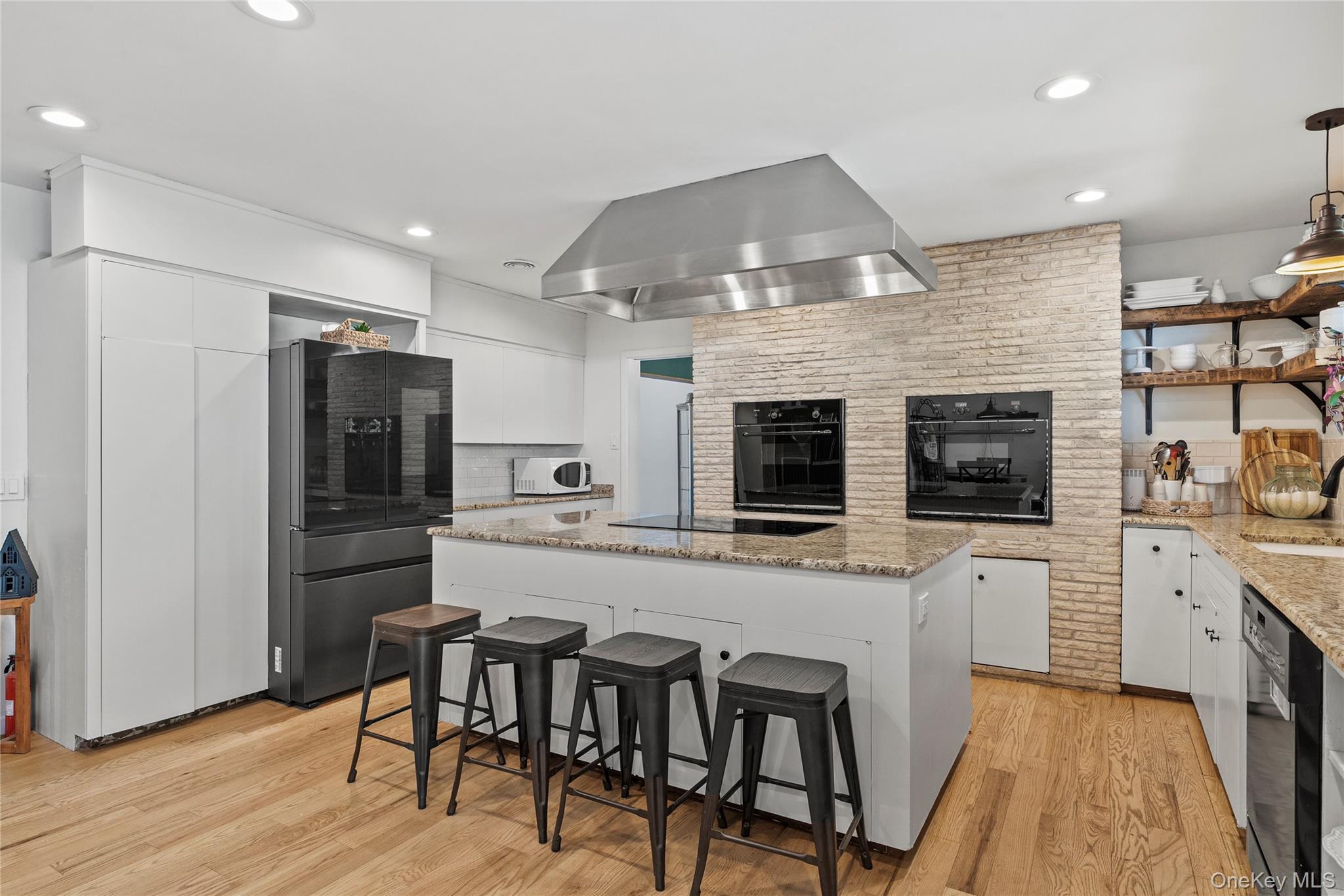 55 Rolling Hill Lane Old Westbury, NY 11568 - Photo 17 of 48 Kitchen featuring a kitchen bar, white cabinetry, black appliances, a center island, and light wood-style floors