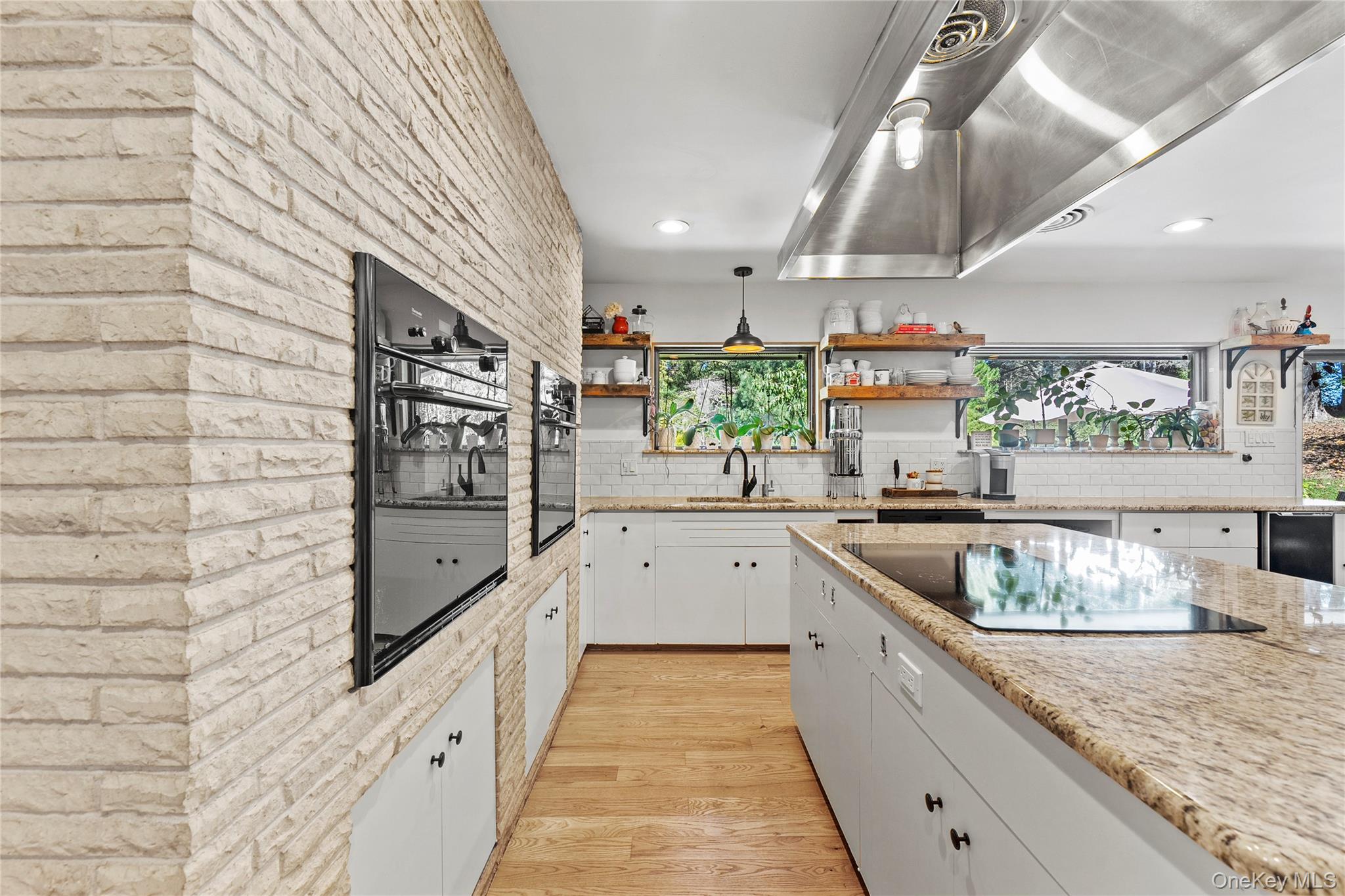 55 Rolling Hill Lane Old Westbury, NY 11568 - Photo 20 of 48 Kitchen featuring wall chimney range hood, white cabinetry, light wood-type flooring, open shelves, and light stone counters