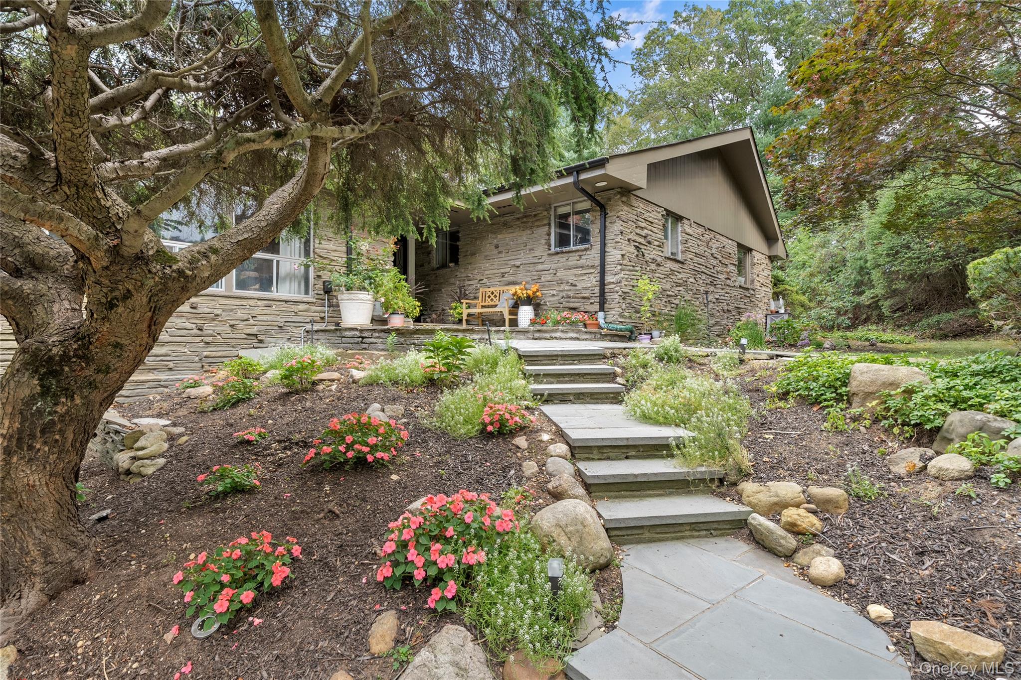 55 Rolling Hill Lane Old Westbury, NY 11568 - Photo 3 of 48 View of front of property featuring stone siding, a patio area, and stairway
