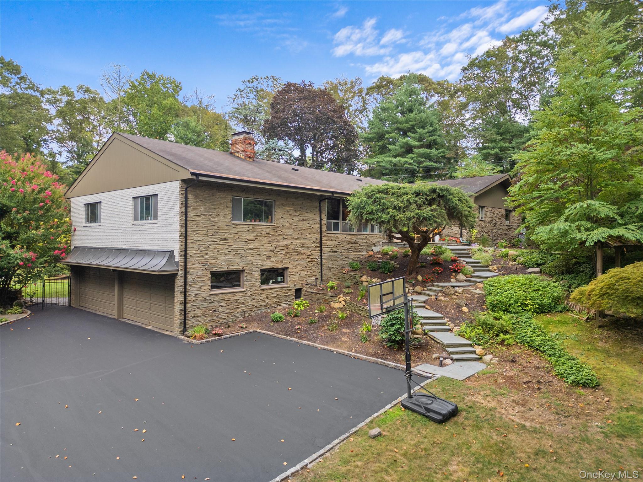 55 Rolling Hill Lane Old Westbury, NY 11568 - Photo 45 of 48 View of home's exterior featuring stairway, asphalt driveway, a chimney, an attached garage, and brick siding