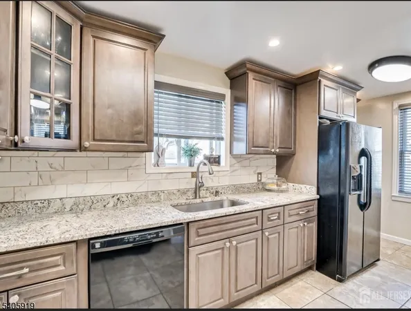 a kitchen with stainless steel appliances granite countertop a sink and a refrigerator