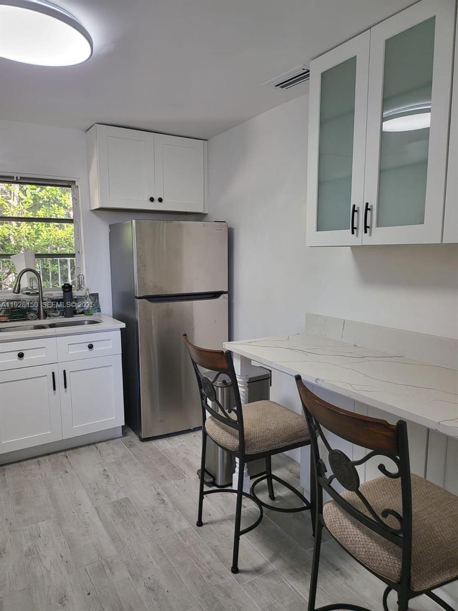 4807 Ponce De Leon, Unit 1 Coral Gables, FL 33146 - Photo 4 of 8 a kitchen with a table chairs refrigerator and cabinets
