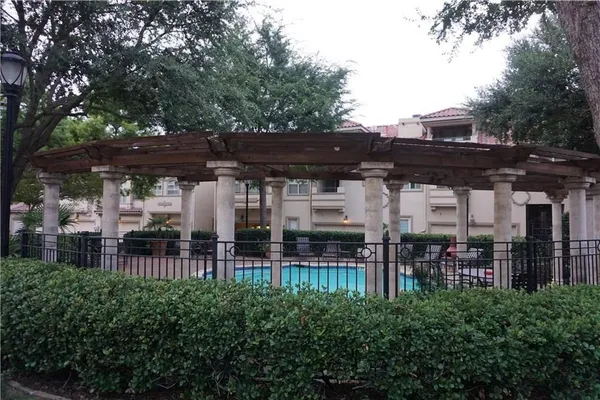 a view of a patio with table and chairs under an umbrella with large trees