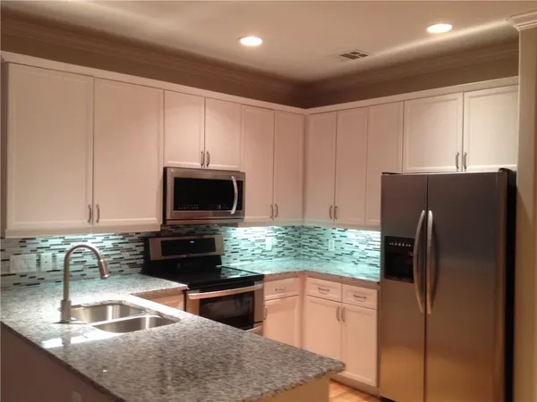 a kitchen with granite countertop a refrigerator and a sink