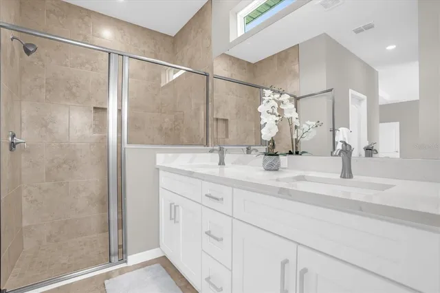 a bathroom with a double vanity sink mirror and shower