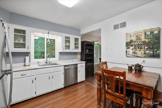 a kitchen with stainless steel appliances granite countertop a stove a sink dishwasher a dining table and chairs with wooden floor