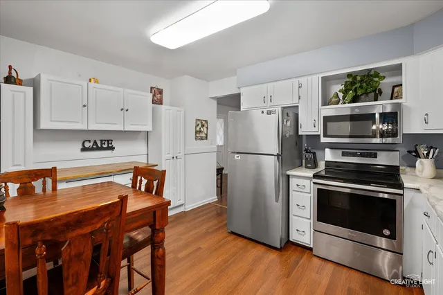 a kitchen with stainless steel appliances a stove a refrigerator and a dining table