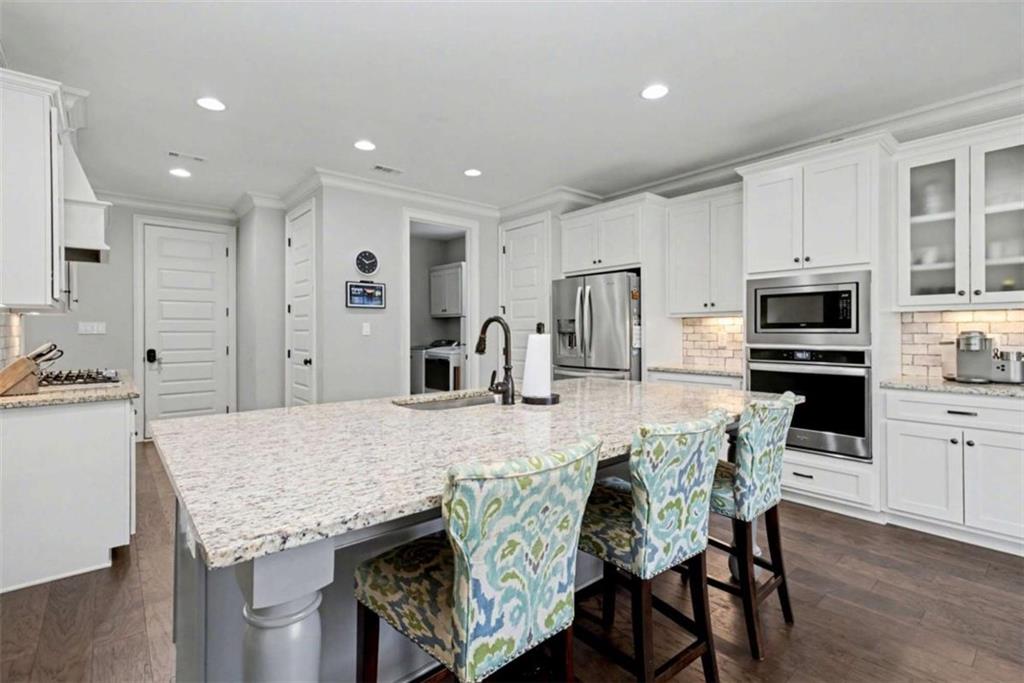 92 Gordon Oaks Way Moreland, GA 30259 - Photo 16 of 54 a kitchen with stainless steel appliances kitchen island granite countertop a kitchen island and chairs in it