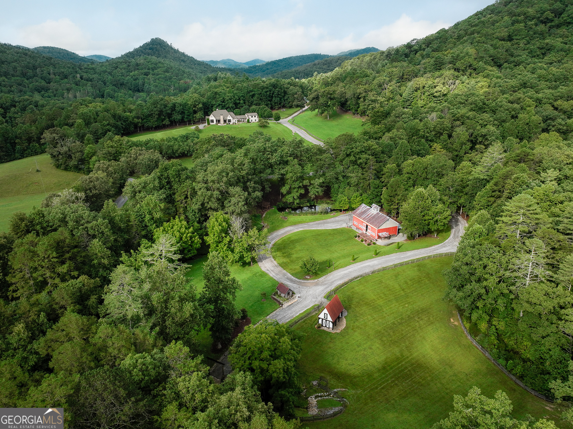 an aerial view of residential house with outdoor space and trees all around