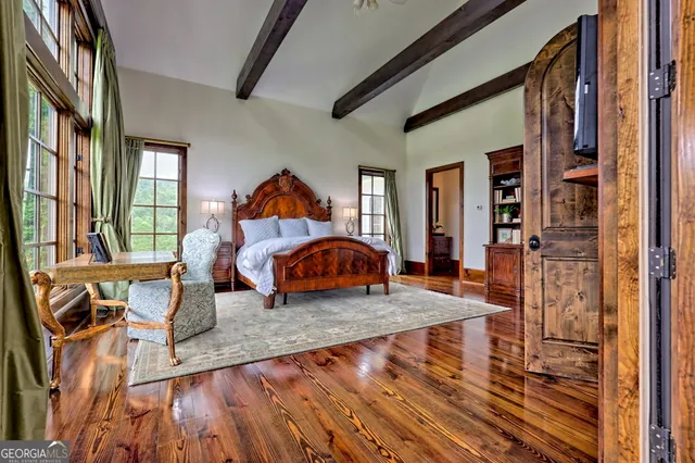a bedroom with a bed a mirror on dresser and a chandelier