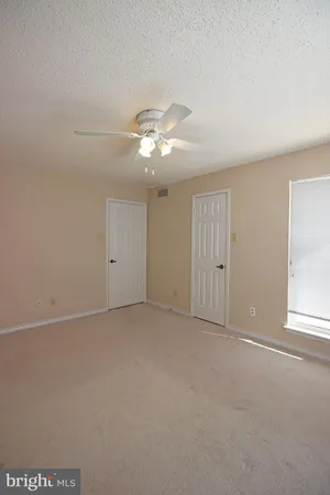 an empty room with chandelier fan and windows