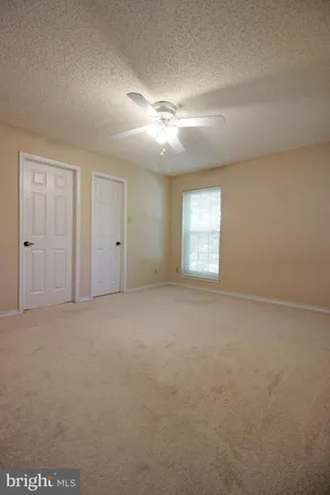 en empty room with windows and ceiling fan