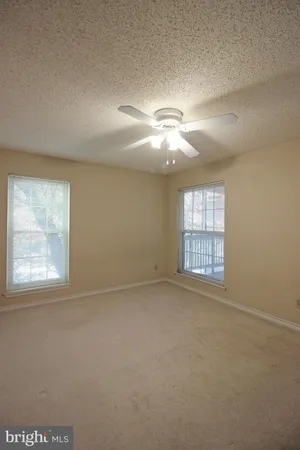 en empty room with windows and chandelier fan