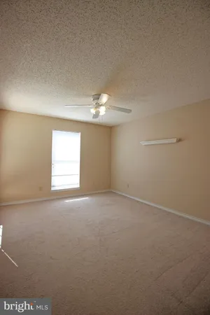 en empty room with windows and chandelier fan